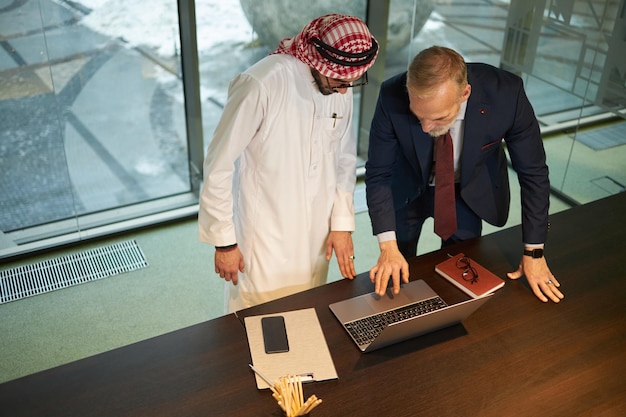 two diverse businessmen using laptop in office