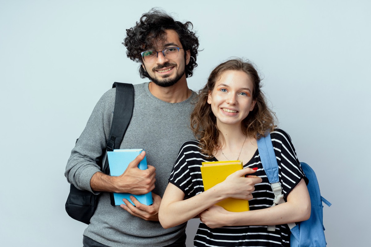 young-couple-man-woman-holding-books-smiling-happy-positive-standing-white-wall (1).jpg