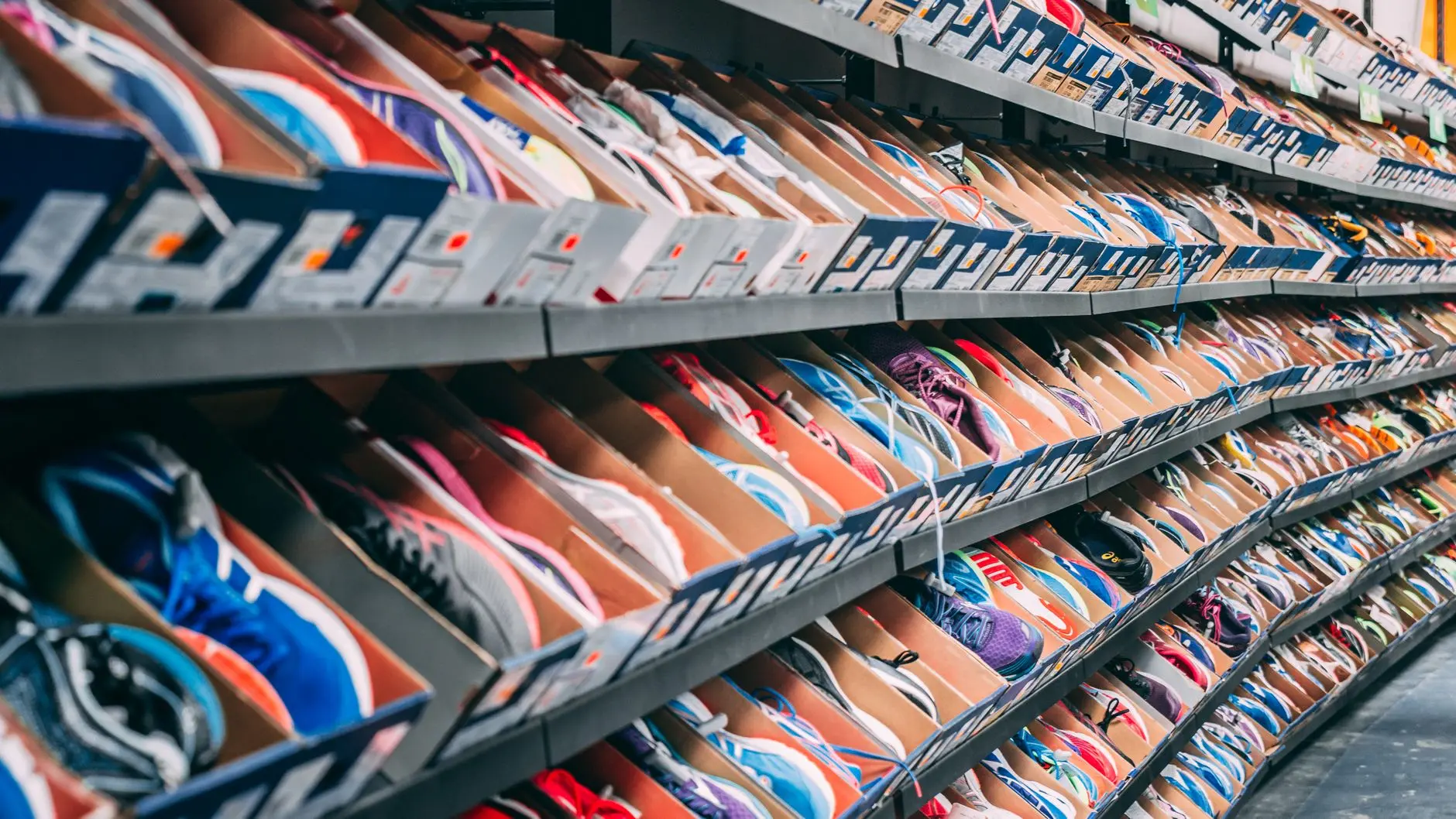 Rows of colorful running shoes displayed in boxes on retail store shelving